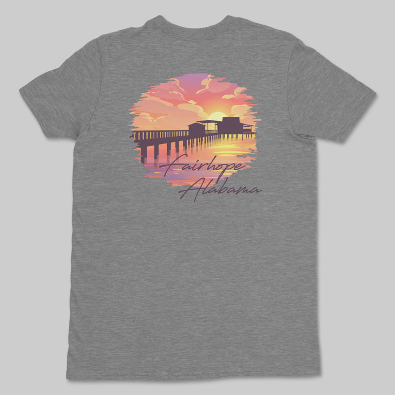 Fairhope Sunset - Tee in gray, adorned with a vibrant sunset illustration of the Fairhope Pier and the text "Fairhope, Alabama" overlooking Mobile Bay.