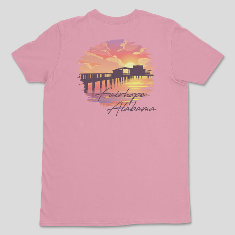 Fairhope Sunset - Tee: A pink t-shirt showcasing a graphic of a sunset over Fairhope Pier, reflecting in the water with the text "Fairhope Alabama.